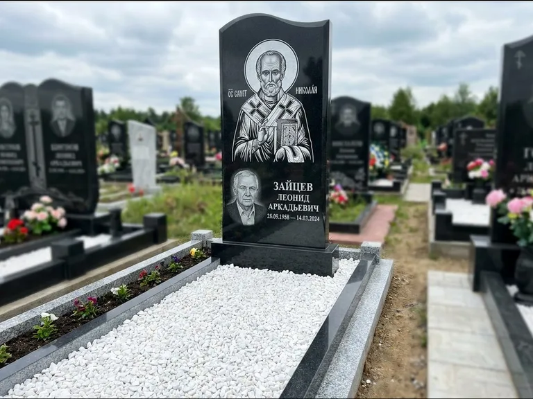 Памятник с гравировкой иконы: стела с крестообразным навершием — икона в резной рамке-киоте, газон без ограды, стриженая трава, работа «Раевская» в Туле