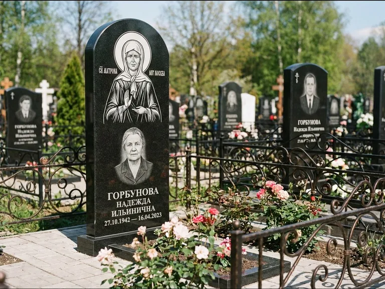 Памятник с гравировкой иконы: стела с арочным верхом и киотом под образ — гравировка образа Матроны Московской, гранитный цоколь с тёмной плиткой, работа «Ковалёв» в Туле