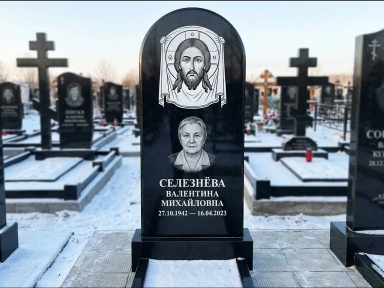 Памятник с гравировкой иконы: небольшая скромная одиночная стела с именной иконой — золочёный нимб на образе, аккуратный участок с газоном, работа «Ковалёв» в Туле