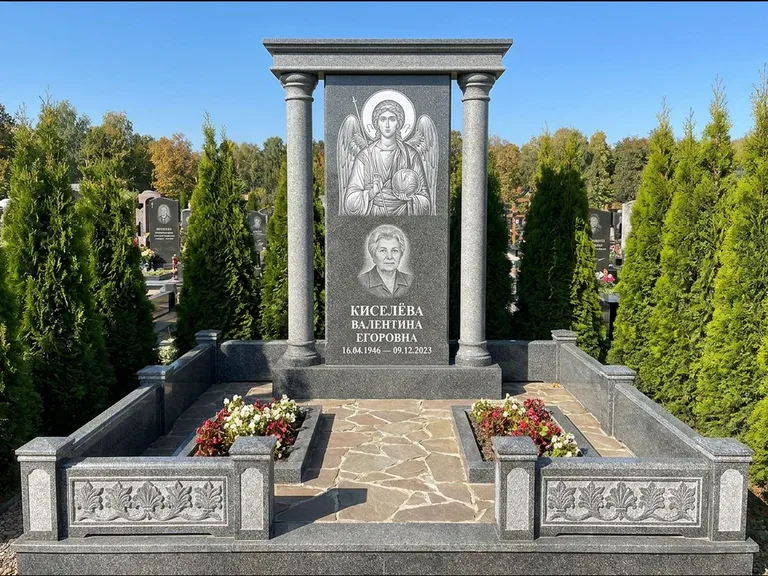 Памятник с гравировкой иконы: массивная стела с двускатным навершием-домиком — гравировка Николая Чудотворца, живая изгородь из туи, работа «Журавлёв» в Туле