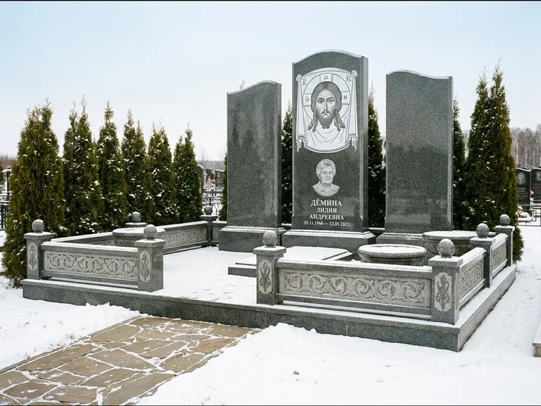 Памятник с гравировкой иконы: узкая вертикальная стела-пилон с ликом — икона в резной рамке-киоте, открытая лужайка без ограды, работа «Одинцов» в Туле