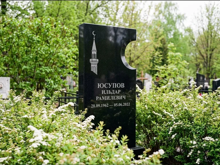 Мусульманский памятник с гравировкой мечети: стела с боковым вырезом в форме полумесяца — гравировка минарета с полумесяцем, низкие кусты спиреи в цвету, работа «Юсупов» в Туле