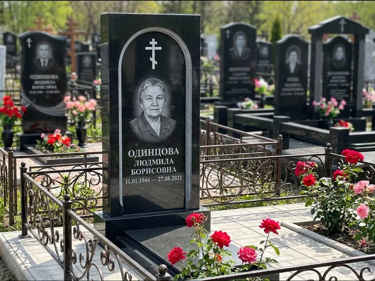 Памятник из чёрного гранита — скромная невысокая стела с крестом с терновым венцом, работа «Лаврентьева» в Туле