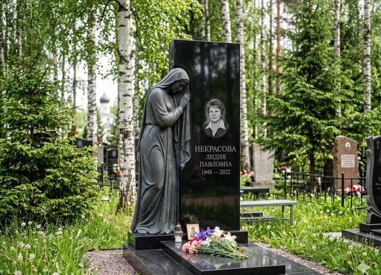 Гранитная фигура скорбящего мужчины у чёрной стелы в Туле